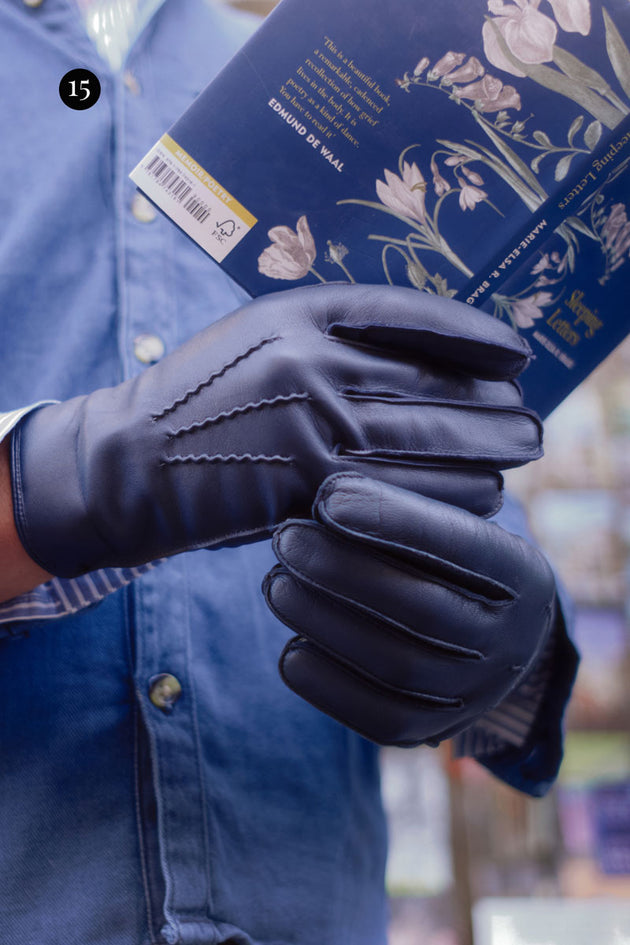 close up show of a man wearing blue leather gloves holding a book