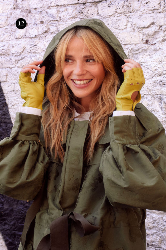 woman wearing fingerless leather driving gloves in lime and a green rain coat