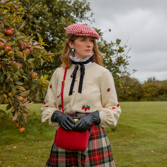 Woman wearing brown leather gloves stood by an apple tree