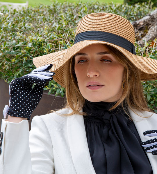 Woman wearing a straw sun hat and spotty cotton gloves in a country garden