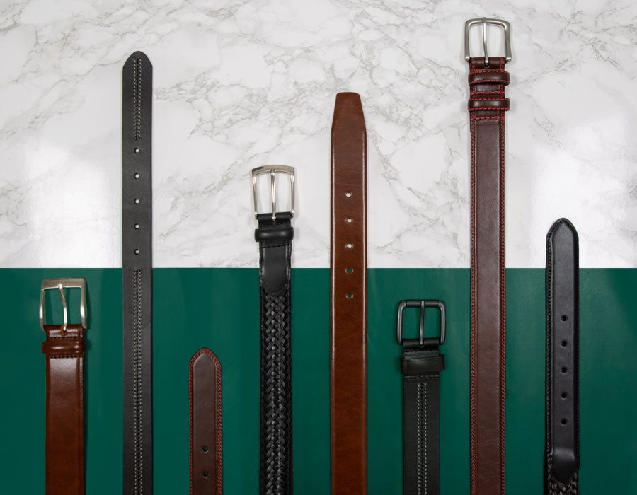Selection of men's brown and black leather belts against a green and marble background