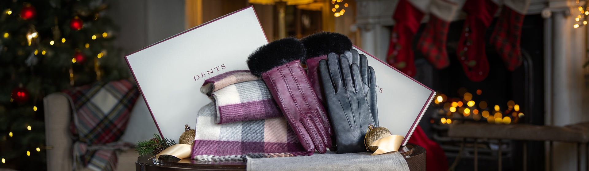 Men's and women's leather gloves and cashmere scarf against a Christmas background