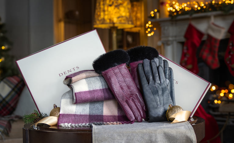 Men's and women's leather gloves and cashmere scarf against a Christmas background