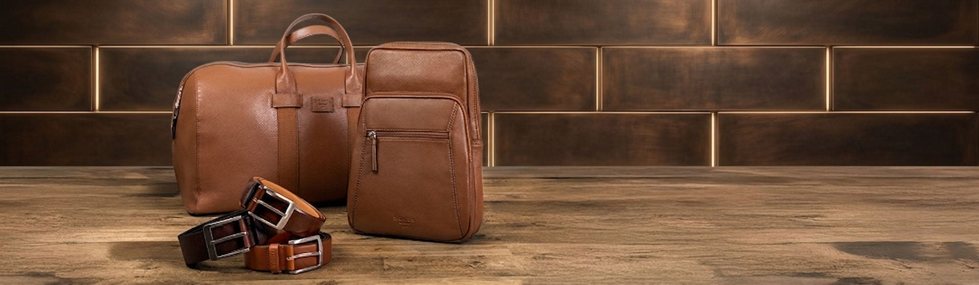 Two caramel leather bags and belts in various styles on a wooden surface with a brick wall background