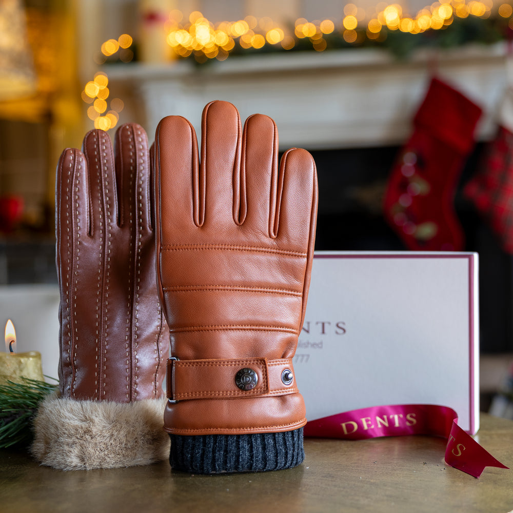 Men's and women's brown leather gloves on a table with a festive background