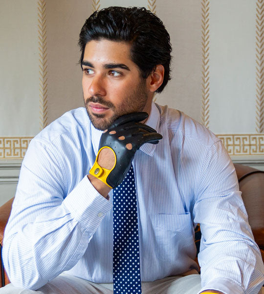 Man wearing a white shirt with a blue tie and a black glove on his hand, sitting in an room