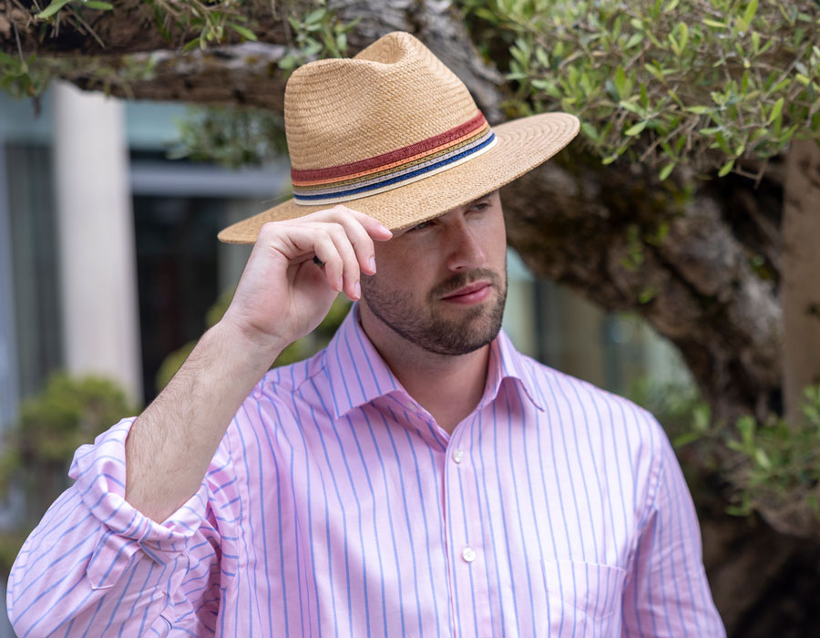 Man wearing a straw hat with a colourful band outdoors.