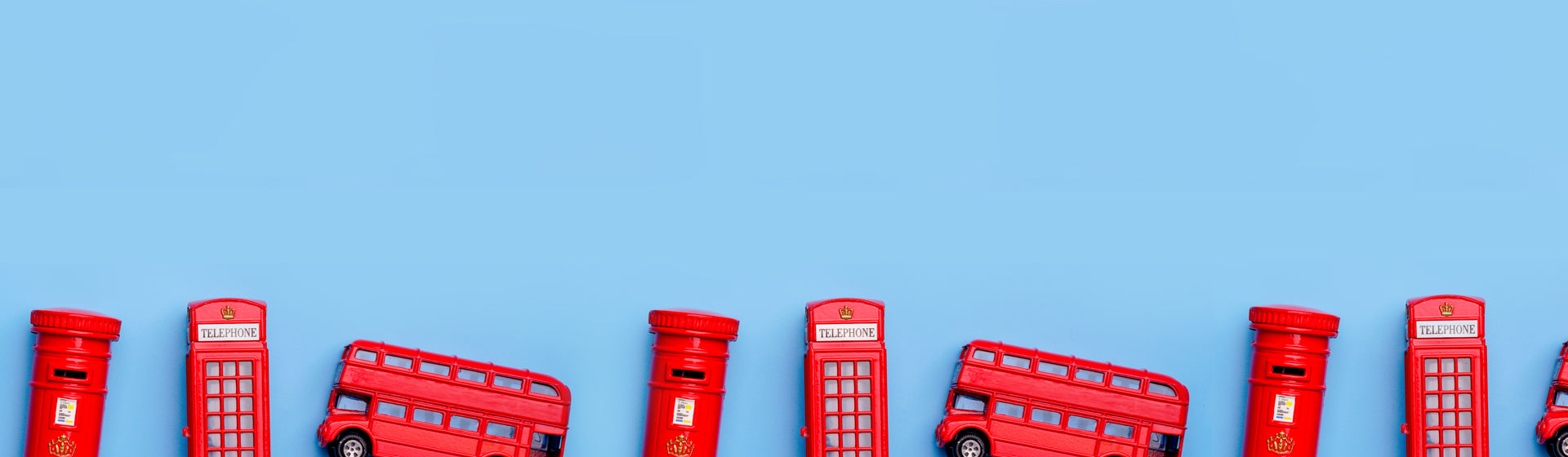 Red toy telephone booth, postbox, and bus on a blue background