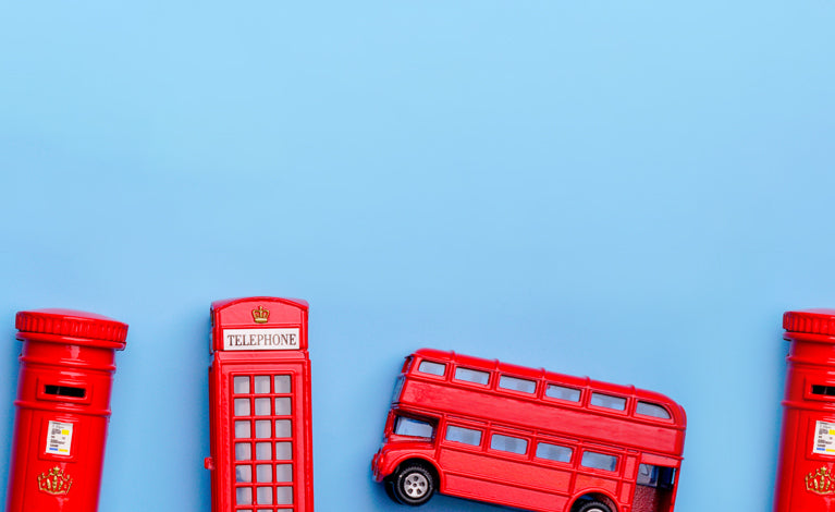 Red toy telephone booth, postbox, and bus on a blue background