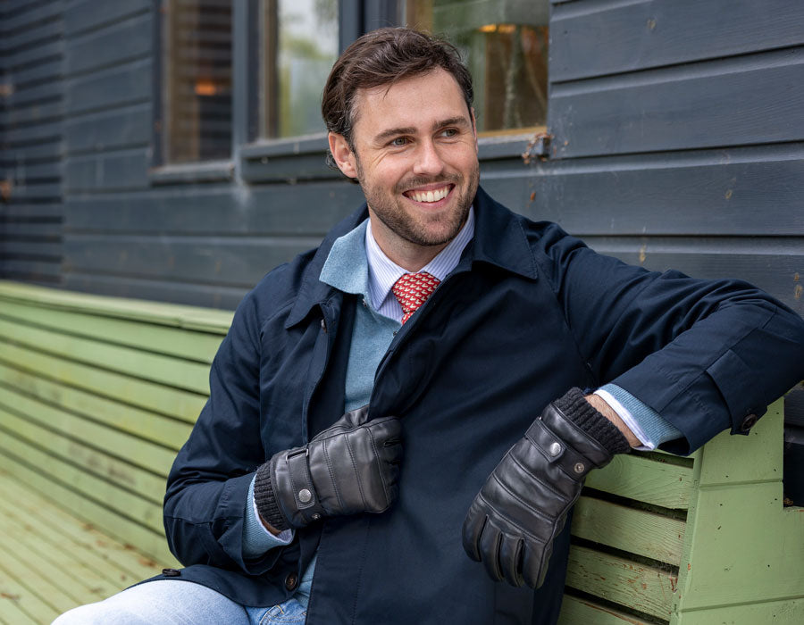 Man wearing leather black gloves outdoors sititing on a bench