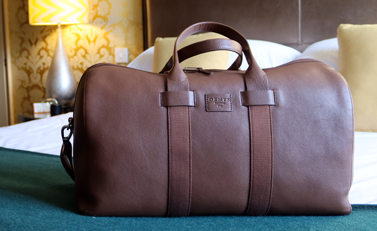 Men's leather bag laid out on bed