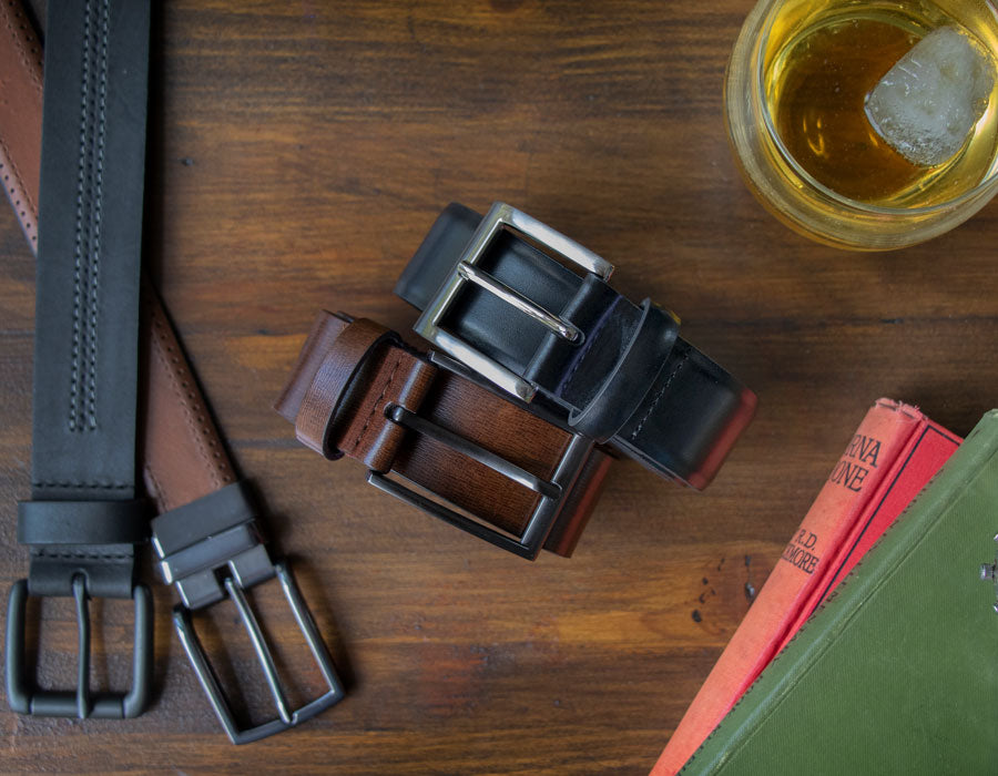 Men's leather belts in various colours and styles laid down on a wooden table