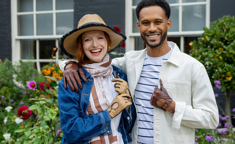Two people standing together in a garden wearing summer hat, scarves and gloves