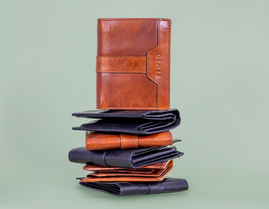 A stack of leather wallets against a solid pale green background.