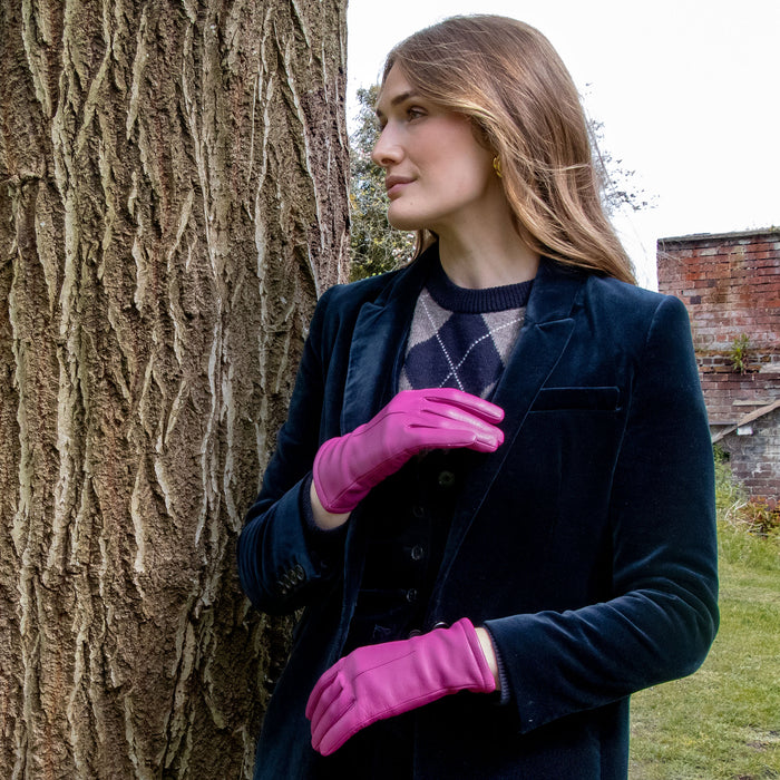 Woman wearing single-point lined leather gloves in hot pink with a velvet blazer