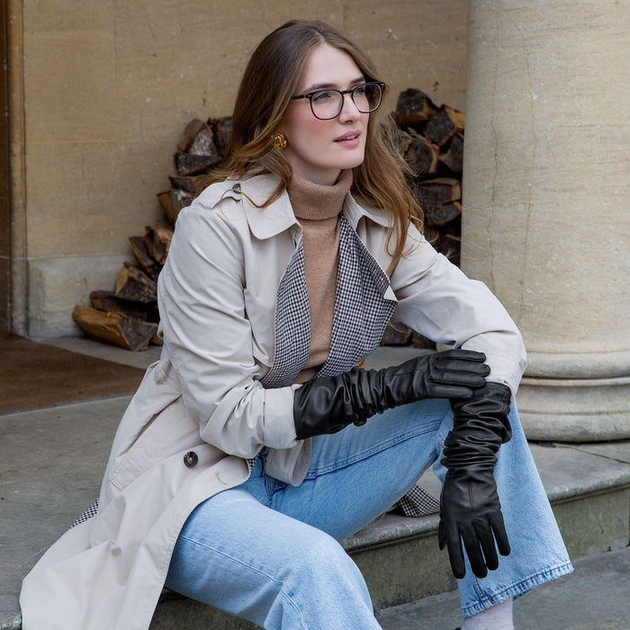 Woman wearing long above-elbow leather gloves in black scrunched down