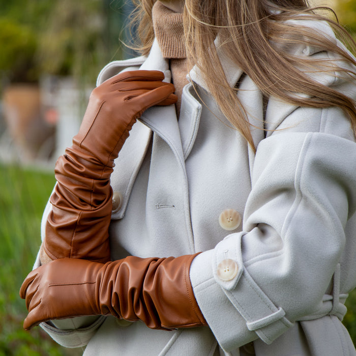 Woman wearing long leather gloves in saddle scrunched down