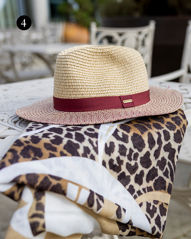 Women's lightweight leopard print scarf with straw hat outside.